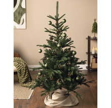 Dekorierter Weihnachtsbaum in einem Wohnzimmer mit grünen matten und glänzenden Christbaumkugeln sowie einer Baumdecke aus Stoff.