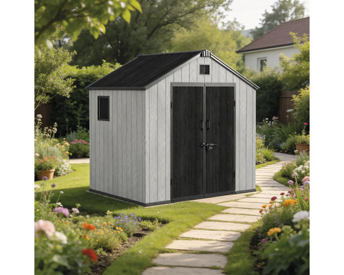 Abri de jardin avec double porte et toit en pente dans un jardin fleuri avec chemin en pierre