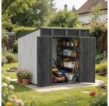 Abri de jardin avec toit en pente et doubles portes ouvertes, équipé d'étagères, d'outils de jardinage et d'une tondeuse dans un jardin fleuri.