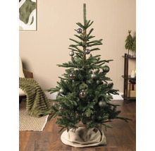 Künstlicher Weihnachtsbaum mit gemusterten Kugeln in einem gemütlich eingerichteten Wohnzimmer mit Holzboden und Weihnachtsdekoration.
