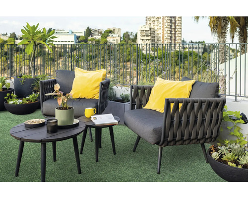 Moderne Loungegruppe mit zwei Sesseln und zwei runden Tischen auf einer Dachterrasse mit Pflanzen und Stadtblick.