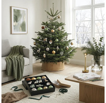 Festlich dekorierter Weihnachtsbaum in einem hellen Wohnzimmer mit Sofa, Holztisch und Weihnachtsschmuck.