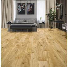 Parquet clair à l'aspect chêne avec des nœuds dans une chambre à coucher lumineuse et moderne avec un lit gris.