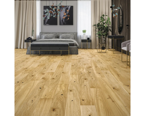 Parquet clair à l'aspect chêne avec des nœuds dans une chambre à coucher lumineuse et moderne avec un lit gris.