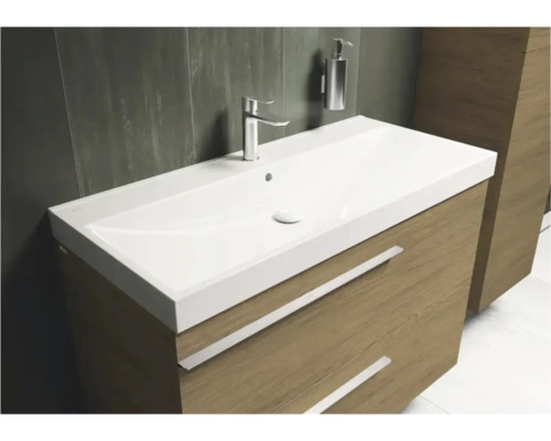 Moderner Waschplatz mit weissem Waschbecken, verchromter Armatur und Unterschrank in Holzoptik mit zwei Schubladen.