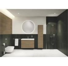 Modernes Badezimmer mit Holz-Waschtisch, rundem beleuchtetem Spiegel, wandhängender Toilette und ebenerdiger Dusche mit dunklen Fliesen.