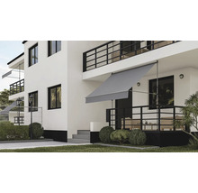 Store banne gris fixé sans perçage sur une terrasse de maison moderne blanche avec jardin.