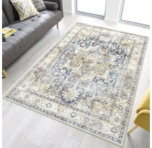 Rechteckiger Orientteppich im Vintage-Stil mit blauem Muster in einem hellen Wohnzimmer mit grauem Sofa.