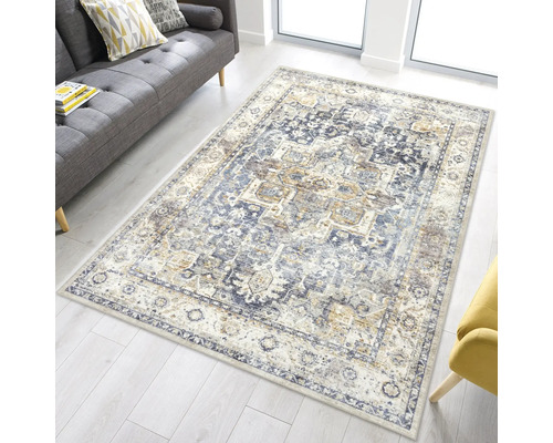 Rechteckiger Orientteppich im Vintage-Stil mit blauem Muster in einem hellen Wohnzimmer mit grauem Sofa.