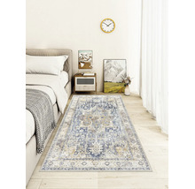 Vintage-Teppich im Orient-Stil mit blau-beigem Muster in einem hellen Schlafzimmer mit Holzboden neben einem grauen Bett.