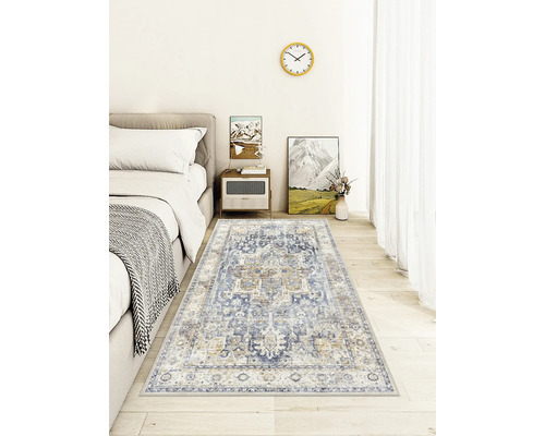 Vintage-Teppich im Orient-Stil mit blau-beigem Muster in einem hellen Schlafzimmer mit Holzboden neben einem grauen Bett.
