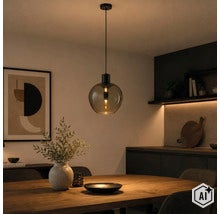 Suspension moderne avec abat-jour rond en verre fumé au-dessus d'une table à manger en bois dans une salle à manger. (Image AI modified or generated)