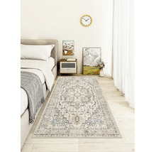 Teppich mit orientalischem Muster in einem hellen, modernen Schlafzimmer auf Holzboden neben einem grauen Bett.
