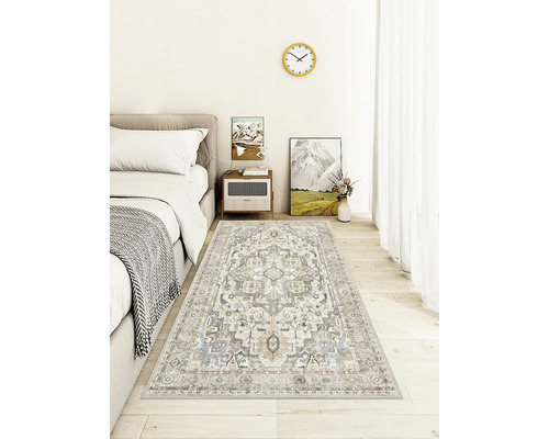 Teppich mit orientalischem Muster in einem hellen, modernen Schlafzimmer auf Holzboden neben einem grauen Bett.