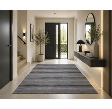 Entrée moderne avec un tapis gris, un escalier en bois, une porte noire et une console suspendue avec un miroir.