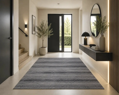 Entrée moderne avec un tapis gris, un escalier en bois, une porte noire et une console suspendue avec un miroir.