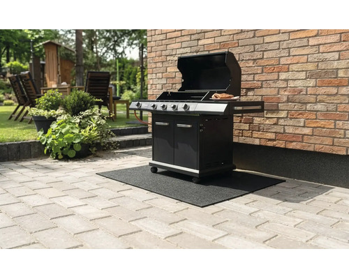 Schwarzer Gasgrill mit offenem Deckel auf einer schwarzen Grillbodenschutzmatte auf einer Steinterrasse vor einer Backsteinwand.