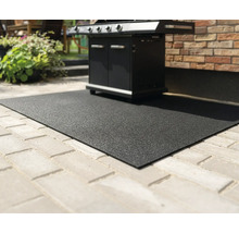 Schwarze, strukturierte Grillschutzmatte auf einer gepflasterten Terrasse unter einem Gasgrill.