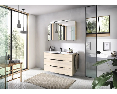 Modernes Badezimmer mit Waschtischunterschrank in heller Holzoptik, schwarzer Armatur, Spiegelschrank und grossem Fenster für eine helle Atmosphäre.