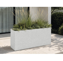 Bac à fleurs rectangulaire aspect granit sur une terrasse moderne, garni de graminées ornementales et de plantes devant une façade.