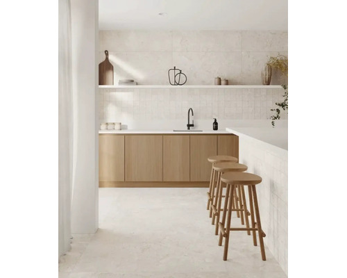Moderne Küche mit hellen Holzschränken, weißen Arbeitsplatten, schwarzer Armatur, Wandfliesen in Steinoptik und drei hölzernen Barhockern.