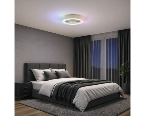 Moderner Deckenventilator mit farbigem LED-Lichtring in einem Schlafzimmer mit grauem Polsterbett, dunklen Vorhängen und Teppich.