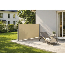 Moderne Seitenmarkise aus Stoff als Sicht- und Windschutz auf einer Steinterrasse mit Sonnenliege und angrenzender Rasenfläche.
