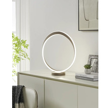 Moderne LED-Tischleuchte in kreisförmigem Ring-Design auf einer Kommode. Hell eingerichteter Raum mit Pflanze, Büchern und Bilderrahmen.