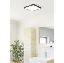 Salle de bains lumineuse avec plafonnier LED carré, lavabo moderne, armoire haute aspect bois et plante d intérieur.