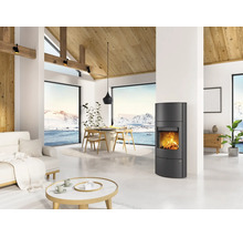Poêle à bois moderne dans un salon lumineux avec de hauts plafonds, des poutres en bois et des fenêtres panoramiques sur un paysage enneigé.