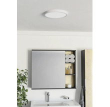 Salle de bain moderne avec armoire de toilette, étagère ouverte, lavabo blanc, robinetterie chromée et plafonnier rond.