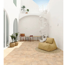 Helle Terrasse mit quadratischen Bodenfliesen in Terrakotta-Optik, einer weißen Wendeltreppe, Topfpflanzen und modernen Sitzmöbeln.