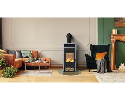 Poêle à bois moderne avec revêtement en pierre et feu dans un salon lumineux avec canapé et fauteuil.
