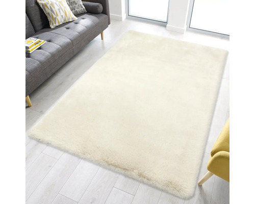 Weicher, rechteckiger Hochflor-Teppich in einem hellen Wohnzimmer mit grauem Sofa und hellem Holzboden.