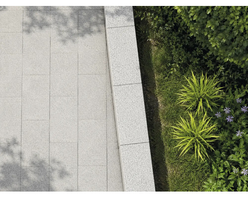 Terrassenplatten und Mauersteine aus Granit im Aussenbereich mit Bepflanzung.