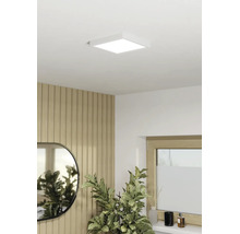 Panneau LED carré comme plafonnier dans une pièce moderne avec mur en tasseaux de bois, miroir et plante d'intérieur.