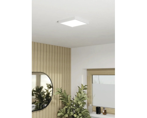 Panneau LED carré comme plafonnier dans une pièce moderne avec mur en tasseaux de bois, miroir et plante d'intérieur.