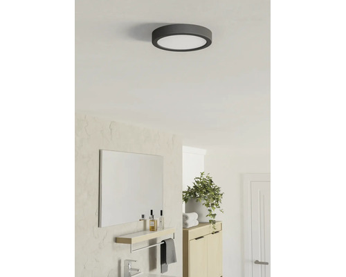 Plafonnier LED rond dans une salle de bains moderne et lumineuse avec miroir, meuble en bois et plante.