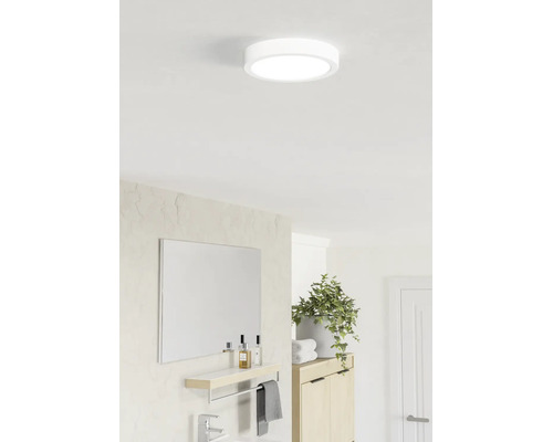 Plafonnier LED rond dans une salle de bain moderne et lumineuse au-dessus d'un miroir avec étagère et d'une plante.