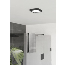 Plafonnier carré et plat noir dans une salle de bain moderne avec douche en verre et carrelage gris.