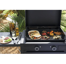 Forge Adour Gas-Plancha mit geöffnetem Deckel, Tacos und Gemüse auf der Grillfläche sowie Grillzubehör auf der seitlichen Ablage.