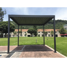 Freistehende Pergola aus Aluminium mit Lamellendach auf einer Holzterrasse im Garten vor einer Grünfläche.
