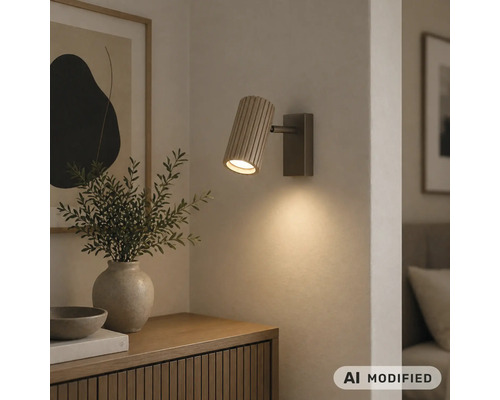 Applique murale avec abat-jour cylindrique en bois strié, diffusant une lumière chaude vers le bas sur un mur.