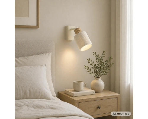 Applique murale en bois et textile à côté d'un lit, diffusant une lumière chaleureuse sur une table de chevet.
