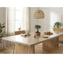 Transparente Tischfolie auf einem hellen Holztisch in einem hellen, aufgeräumten Esszimmer mit einer Korblampe und einem Bonsai.
