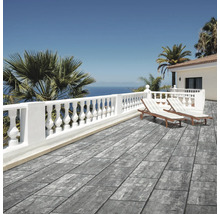 Terrasse moderne avec dalles en aspect pierre grise, balustrade blanche, chaises longues et vue sur mer dans un cadre méditerranéen lumineux.