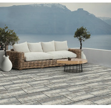 Dalles de terrasse rectangulaires de grand format en gris et blanc sur une terrasse moderne avec mobilier de jardin et vue sur mer.