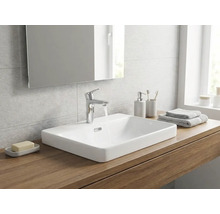 Modernes Badezimmer mit weißem Aufsatzwaschbecken aus Keramik auf einer Holzplatte, verchromter Waschtischarmatur und einem Spiegel.
