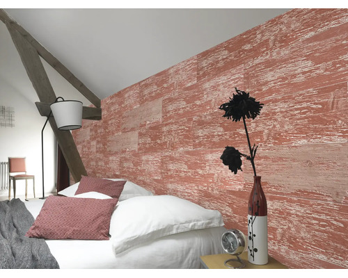 Helles Schlafzimmer mit strukturierter Wand in roter Holzoptik, weissem Bettzeug, rustikalem Holzbalken und einer modernen Stehlampe.