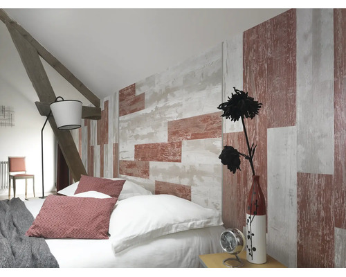 Schlafzimmer unter Dachschräge mit Tapete in Holzoptik, Bett mit Kissen, Stehlampe und sichtbaren Holzbalken.